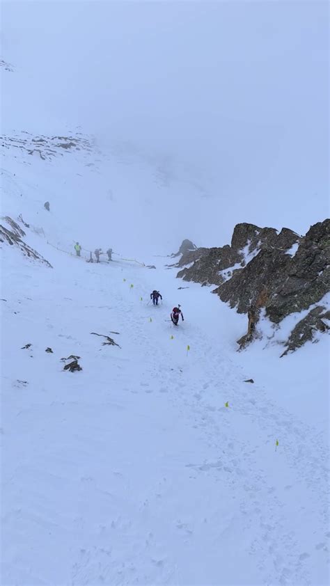 Atleti di scialpinismo in azione su un crinale montano, con vista panoramica.