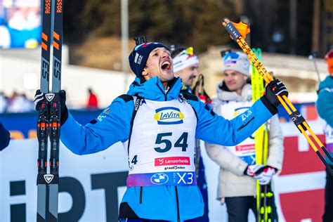 atleta di biathlon che corre con gli sci da rullini