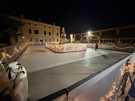 Vista aerea di una pista di pattinaggio su ghiaccio all'aperto in una piazza cittadina durante il periodo natalizio.
