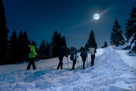 Vista notturna di una ciaspolata sulla neve con la luna piena
