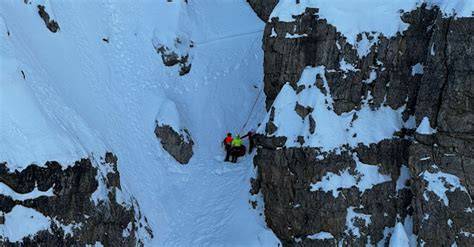 Dettaglio del canalone ripido con neve ghiacciata e piccozza piantata nella roccia.