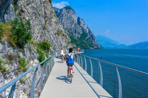 Vista panoramica del Lago di Garda con piste ciclabili che costeggiano il lago e attraversano uliveti.