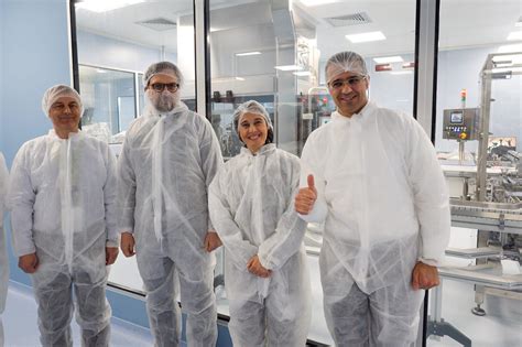 Foto di studenti in visita a uno stabilimento produttivo di dispositivi medici, con indosso camici e copriscarpe.