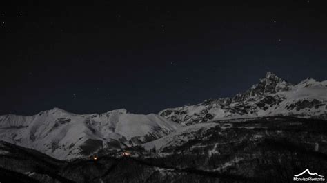 Panoramica del Monviso durante una ciaspolata notturna a Ostana, con la luna piena che illumina il paesaggio innevato.