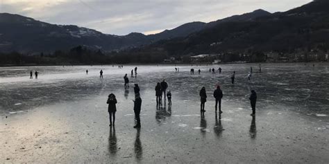 Pattinatori su un ampio lago ghiacciato in un paesaggio alpino