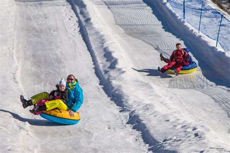 Famiglia che fa snowtubing in un parco divertimenti sulla neve