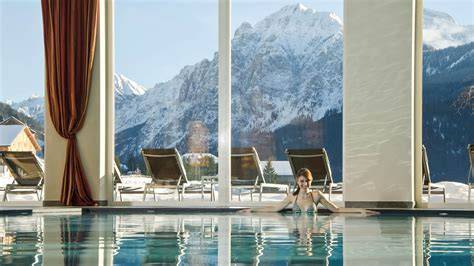 Coppia che si rilassa in una piscina panoramica con vista sulle montagne innevate