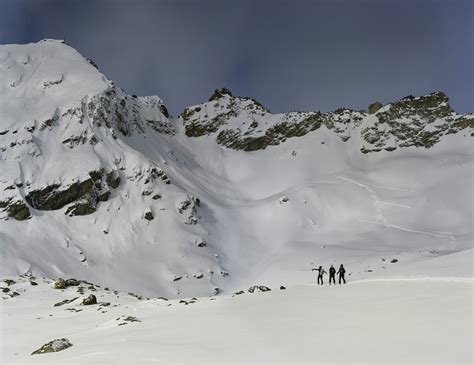 Un rider in piedi su uno splitboard in cima a una montagna innevata, pronto per la discesa.