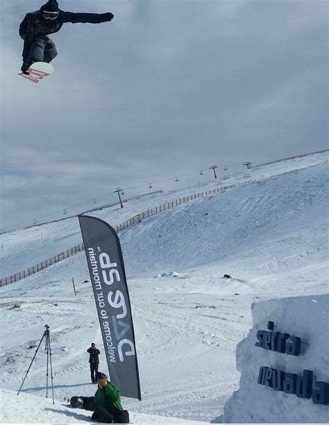 Un rider esegue un salto spettacolare in uno snowpark ben attrezzato, con rampe e ostacoli.