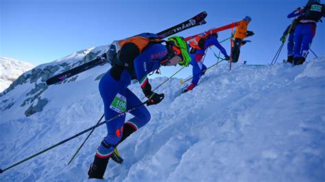 Una guida di sci alpinismo che mostra la via a un piccolo gruppo di allievi su un pendio innevato.