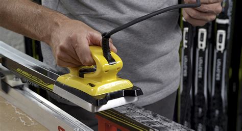 Primo piano di un ferro da scioline che scioglie la sciolina su una soletta di sci