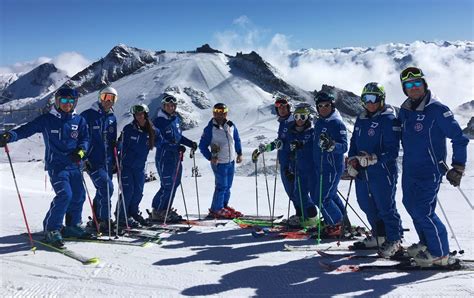 Maestri di sci che insegnano a un gruppo di bambini su una pista innevata.