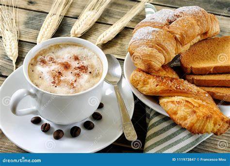 Immagine di una colazione italiana con cappuccino e brioche fresche.