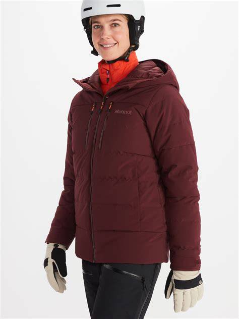 Schema der Marmot Wm's Slingshot Jacket mit hervorgehobenen Funktionen wie Kapuze, Schneefang, Taschen und Belüftungsöffnungen.