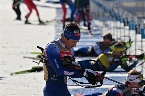Atlete di biathlon in azione durante una gara di inseguimento, con i fucili appoggiati a terra al poligono.