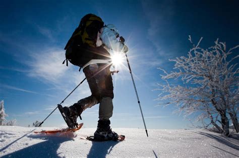 Uomo con ciaspole che cammina su un sentiero innevato al chiaro di luna