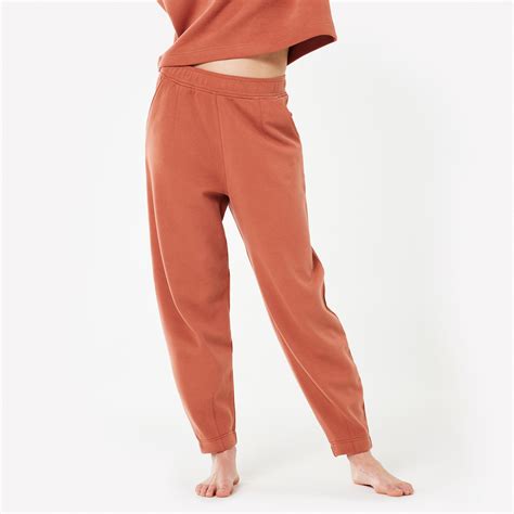 Donna che indossa pantaloni felpati per un'attività di stretching in un ambiente domestico.