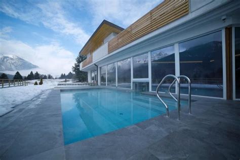 Interno di un'area wellness con piscina riscaldata e vista sulle montagne.