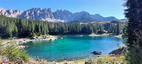 Ciclisti che pedalano lungo un lago alpino circondato da montagne verdi