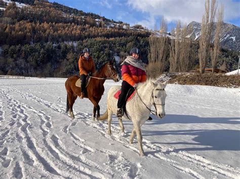 coppia che fa un'escursione a cavallo sulla neve in un paesaggio montano