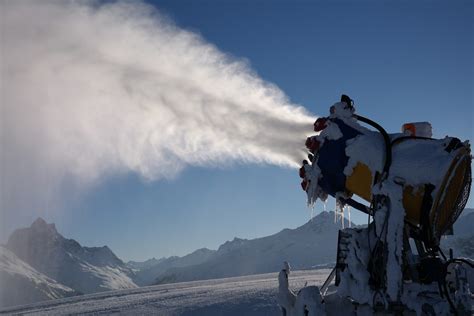 Immagine di una pista da sci con cannoni da neve attivi in un paesaggio montano.