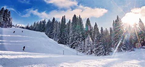 Panorama alpino italiano con piste da sci e rifugi di montagna sotto il sole.