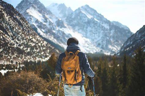 Fotografia di un escursionista con zaino da trekking ben equipaggiato e reflex agganciata esternamente