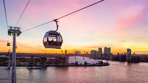 Vista notturna dello skyline di Londra con la funivia IFS Cloud Cable Car illuminata, che attraversa il Tamigi.