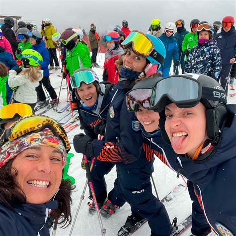 Maestri di sci sorridenti con gruppi di allievi di diverse età