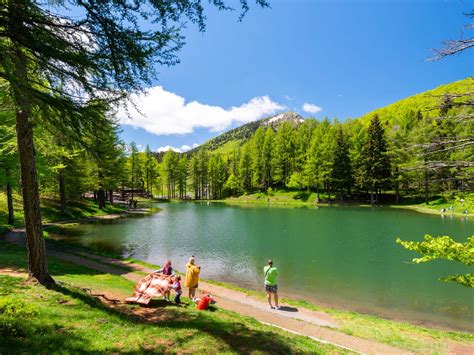 Immagine del Lago della Ninfa con un'area giochi per bambini innevata e piste da sci sullo sfondo.