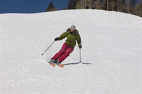Donna che scia su pista innevata con giacca da sci colorata