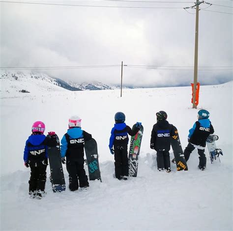 Bambini che imparano a fare snowboard con un istruttore