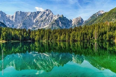 Laghi di Fusine con montagne innevate riflesse sull'acqua ghiacciata