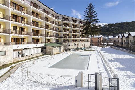 Esterno del Grand Hotel del Parco con facciata in stile montano e montagne innevate sullo sfondo