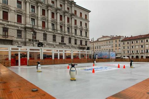 Vista generale della pista di pattinaggio su ghiaccio a Trieste, con pattinatori di varie età e persone che osservano dall'esterno.