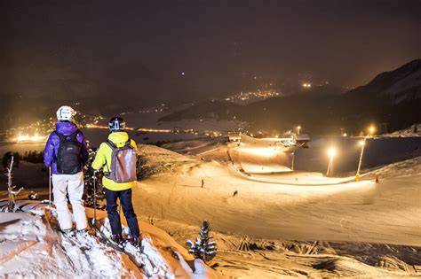 Sciatori su una pista illuminata di notte