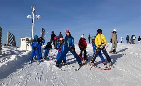 Maestri di sci che insegnano a un gruppo di sciatori su una pista innevata a Sappada