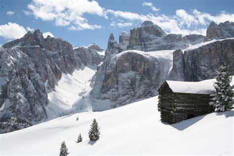 Panorama delle Dolomiti innevate con un locale tipico in primo piano a Sappada