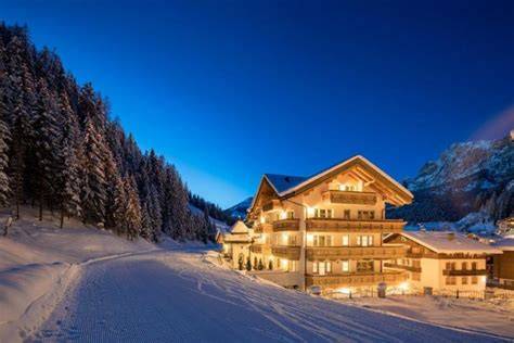 famiglia felice che scia vicino al proprio hotel sulle piste