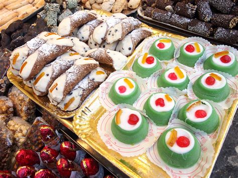 Una selezione di dolci tipici siciliani, tra cui cassate e cannoli, esposti in una vetrina colorata
