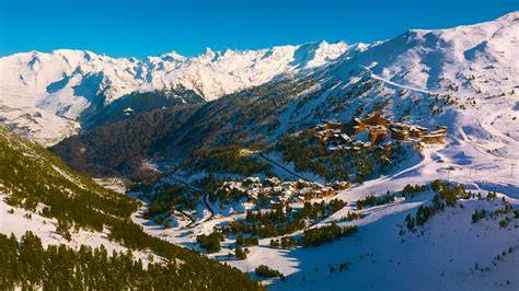 Vista aerea di un canalone innevato in montagna, potenzialmente parte di un itinerario scialpinistico.