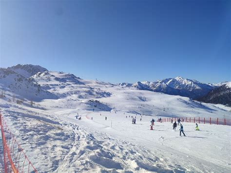 Panorama di un comprensorio sciistico con piste innevate e montagne sullo sfondo