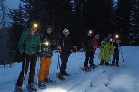 Foto di gruppo di partecipanti felici durante una ciaspolata notturna