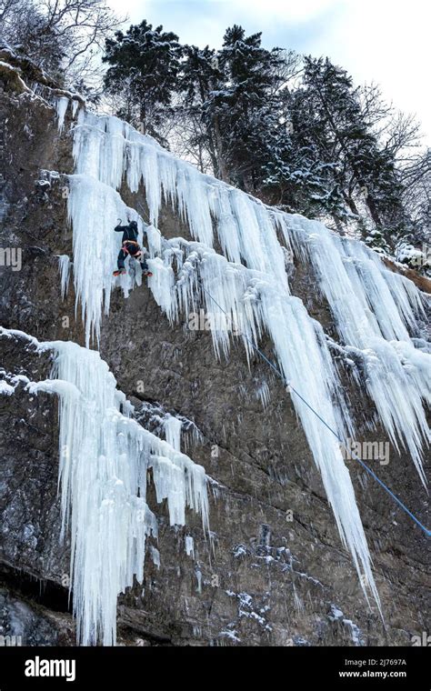 Una cascata di ghiaccio con un arrampicatore intento a scalarla