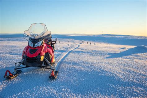 Motoslitta che attraversa un paesaggio innevato al tramonto