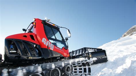 Vista laterale del PistenBully 600 Polar con lama e fresa in azione