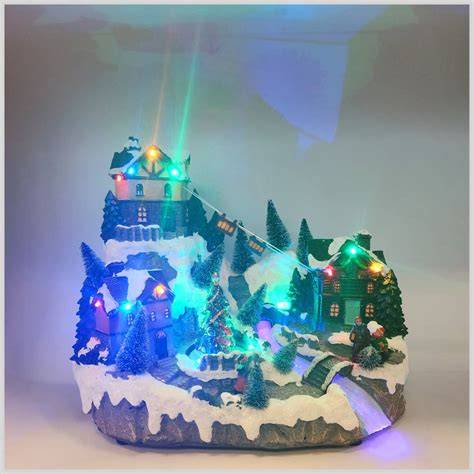 Villaggio natalizio in miniatura con luci LED, personaggi sciatori e funivia in movimento.