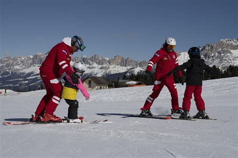 Maestri di snowboard che insegnano ai bambini a sciare su un pendio innevato con le montagne sullo sfondo