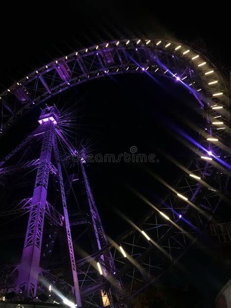 ruota panoramica illuminata di notte in una piazza cittadina, con sfondo di edifici storici e decorazioni natalizie