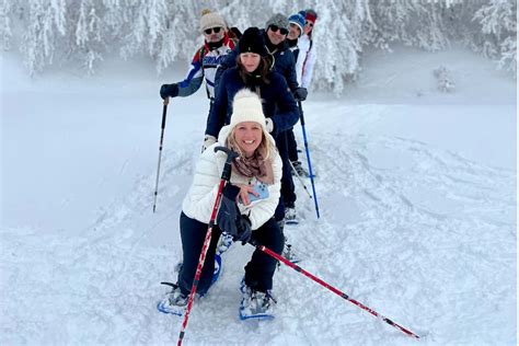 Gruppo di persone con ciaspole in un bosco innevato